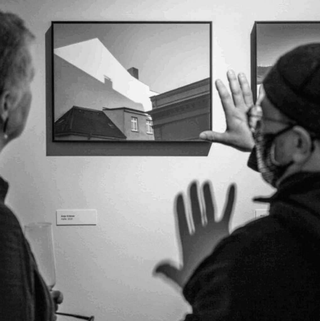 Ausstellungsbesucher besprechen zwei Fotografien